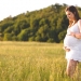 Pregnant woman holding belly in nature